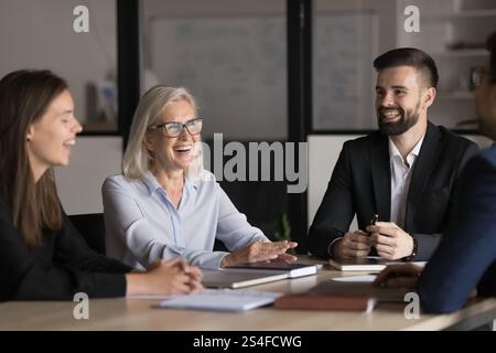 Laughing teammates, diverse professionals negotiating in modern boardroom Stock Photo