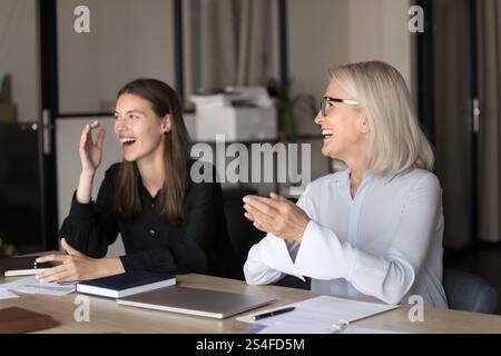 Two laughing businesswomen sitting at table during business meeting Stock Photo
