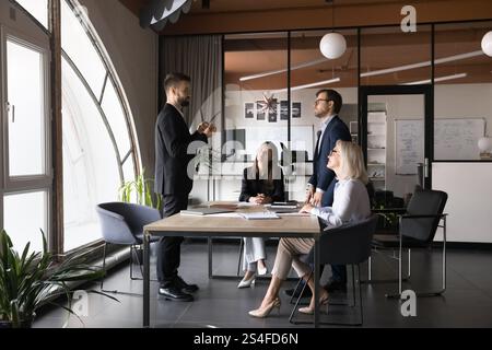 Serious team leader talking to colleagues gathered in boardroom Stock Photo