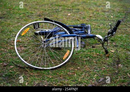 View of a blue broken bicycle lying on green grass. Stock Photo
