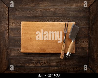 a wooden cutting board with a fork and a knife Stock Photo