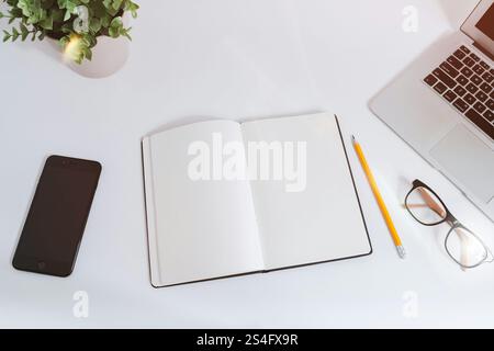 An open empty notebook on a white desk next to a computer Stock Photo