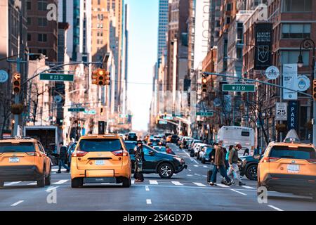 New York City, New York - March 3, 2024:  Street scene from Midtown Manhattan with cars, yellow taxi cabs, people and buildings. Stock Photo