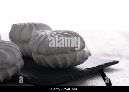 White marshmallows on black slate plate on white background Stock Photo