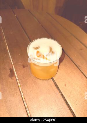 Whiskey Sour cocktail in a round glass on a table. Flashlight photo filter oldschool vintage. Stock Photo