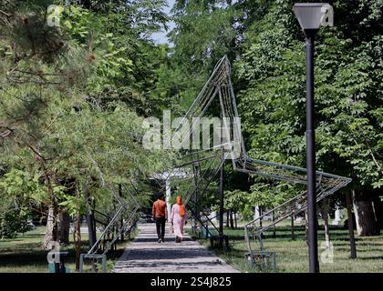 A couple walks under a metallic star toward the sculptures of poets Alisher Navoi and Abdur Rahman Jami in Samarkand's Central Park, Uzbekistan. Stock Photo