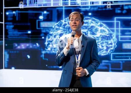 Computer scientist speaking at tech event, explaining impact of artificial intelligence technology. Data analyst presenting risks and threats associated with AI during discussion panel Stock Photo