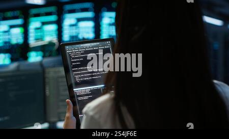 Data center software developer responsible for installation of networking equipment solving tasks on device. Close up of woman doing maintenance on server room infrastructure using tablet, camera A Stock Photo