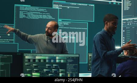 Governmental hackers analyzing cyber threats on big screens, managing important database hacking activity in high tech agency office. Work on cyber defense to protect national security. Camera A. Stock Photo