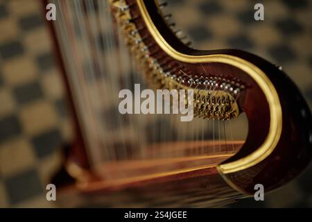 Close up on tuning pins and levers of antique harp with wooden curved frame captured against checkered floor indoors, copy space Stock Photo
