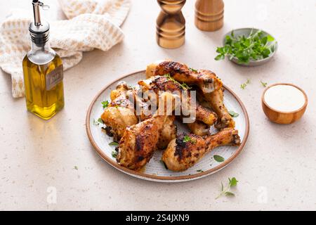 Appetizing roasted or grilled chicken legs garnished with herbs, served on a kitchen table Stock Photo