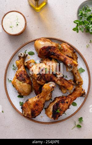 Appetizing roasted or grilled chicken legs garnished with herbs, served on a kitchen table Stock Photo