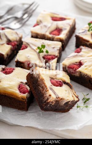 Cheesecake brownies with raspberry and cream cheese swirl stacked on a plate Stock Photo