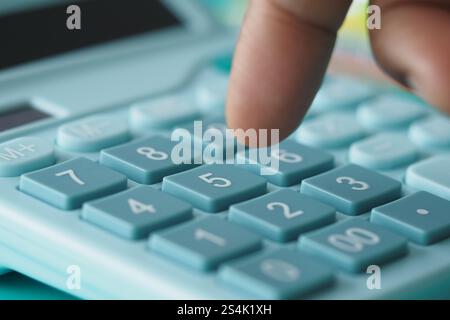 A CloseUp of a Hand Firmly Pressing a Button on a Calculator Device Stock Photo