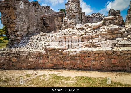 A stone wall with a grassy area in between. The wall is old and has a lot of cracks Stock Photo