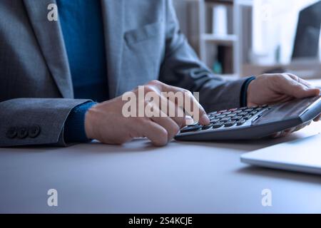 Businessman in the office using a calculator and laptop computer to review a return on investment, budget, income, and profit planning Stock Photo