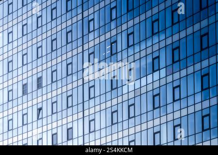 A single illuminated office window in a modern steel and glass bank building. Working late in an office tower. Office building glass windows facade in Stock Photo