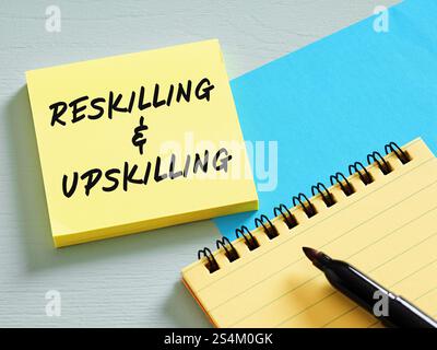 Sticky note with reskilling and upskilling handwritten, education and training concept, notepad and marker on blue and gray background Stock Photo