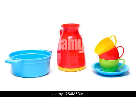 Plastic multicoloured toy dishes decanter, jug, bowl, pot, plates and cups isolated on a white background Stock Photo