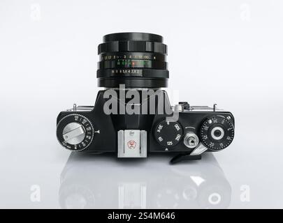Soviet black film camera ZENIT TTL lying with the lens up isolated on a white background with reflection Stock Photo