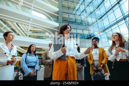 A diverse group of business professionals engaged in a training session at a modern law firm. The image captures a speaker holding a laptop, deliverin Stock Photo
