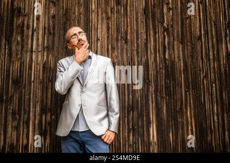 Portrait of worried businessman who is messaging on phone. Wooden background. Stock Photo