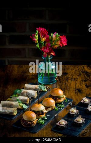 Elegant display of vegetable and courgette rolls, pulled pork and cabbage mini burgers, and rare tuna steaks with mayonnaise and seeds Stock Photo