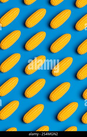 Stylized corn cobs arranged on a vivid blue background, symbolizing critique of junk food and plastic culture The image showcases artificiality with v Stock Photo