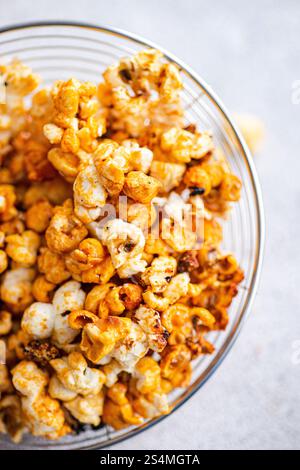 Top view of a glass bowl overflowing with caramel-coated popcorn, showcasing a mix of golden hues and crunchy textures. Stock Photo