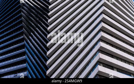 A close view of a modern skyscraper demonstrates contrasting architectural details, featuring alternating patterns of blue glass and white panels. Stock Photo