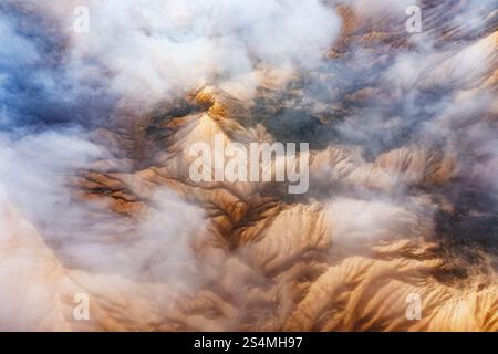 Stunning aerial view of rocky mountain peaks partially obscured by white clouds The landscape reveals a dramatic contrast between jagged ridges and so Stock Photo