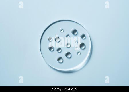 A close-up image of clear water drops on a glass surface, captured in soft blue lighting This minimalist composition highlights the purity and clarity Stock Photo