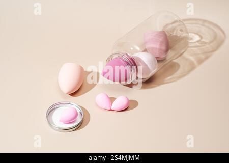 A variety of pastel-colored cosmetic sponges are artistically arranged on a neutral background They offer a modern approach to makeup application, enh Stock Photo