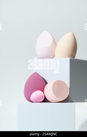 A collection of colorful cosmetic sponges in different shapes and sizes displayed on minimalist blocks, perfect for blending makeup and enhancing any Stock Photo