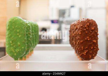 Assorted colorful gelato bars on sticks, featuring green and chocolate coatings These frozen treats are displayed in a rustic Italian bakery setting, Stock Photo