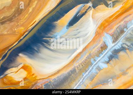 A captivating abstract image featuring flowing textures in vibrant hues of blue, orange, and yellow The dynamic movement and color blending create a s Stock Photo