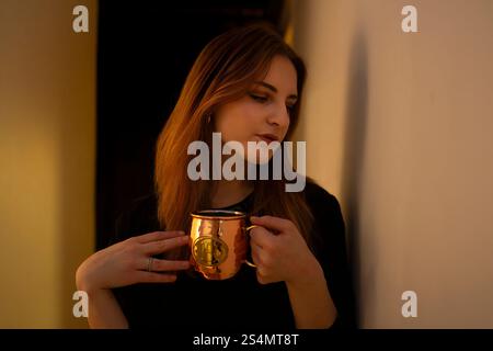 Young woman enjoying a warm beverage in a cozy setting Stock Photo