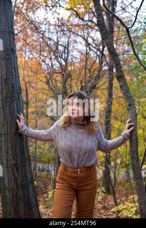 Young woman poses thoughtfully among vibrant autumn trees Stock Photo