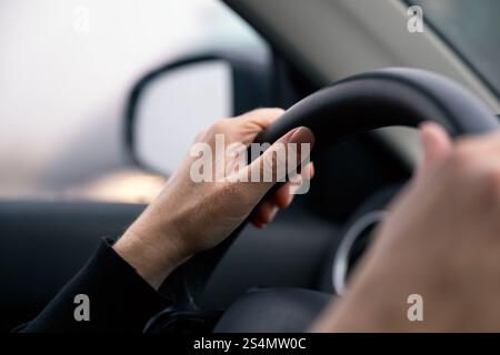 Closeup of female hands on automobile steering wheel, selective focus Stock Photo
