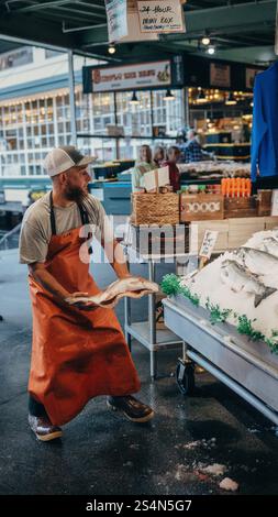 A fish monger throwing salmon at the iconic fish market at Pike Place Market in Downtown Seattle Stock Photo