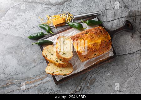 Homemade crispy jalapeno cheese bread sliced ??into thick slices close-up on cutting board on table. Horizontal top view from above Stock Photo