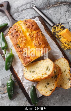 Fresh baked sliced bread loaf with Cheese and Jalapeno closeup on the wooden board on the table. Vertical top view from above Stock Photo