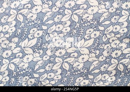 A blue fabric with white flowers and leaves in a close up view Stock Photo
