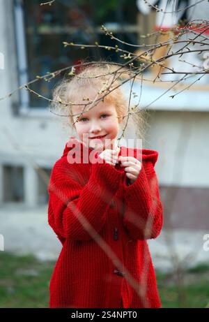 Smiling happy little girl in spring garden near her home Stock Photo