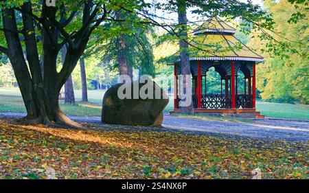Wooden belvedere, big stone and pedestrian path in autumn city park Stock Photo