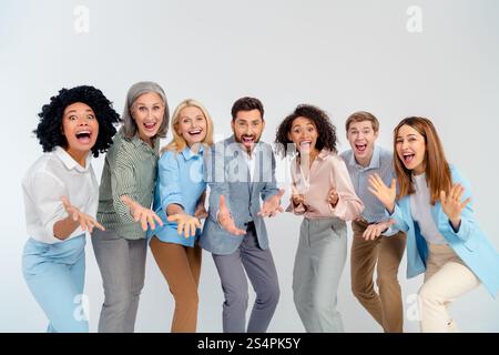 Diverse smiling professionals in formalwear joyfully pose together in bright atmosphere on grey background Stock Photo