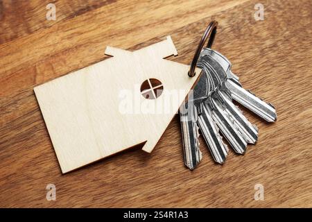 Metal keys with wooden house-shaped keychain on board. Concept of real estate ownership or buying a new home. Top view Stock Photo