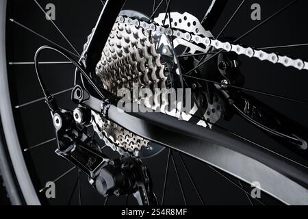 Shifting gears on rear transmission of bicycle on black background. Rear derailleur, cassette and chain. Stock Photo