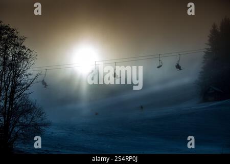 Beautiful silhouette photo of ski lifts shot against bright sun in mountains Stock Photo