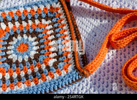 Small women's bag made of cotton yarn. Multi-colored handbag on a light background. Stock Photo